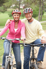 Senior couple riding bicycle in park
