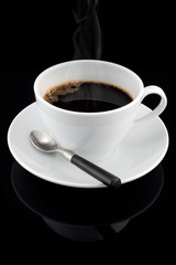 Cup of hot streaming coffee over black background