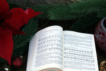 Aufgeschlagenes Gesangbuch vor Tannenzweig und Adventsstern