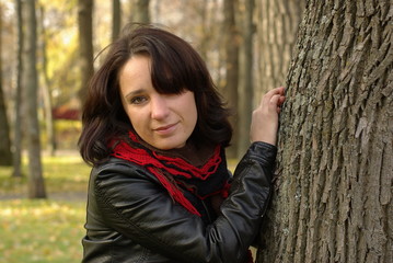 Portrait of a girl leaning against a tree in the park