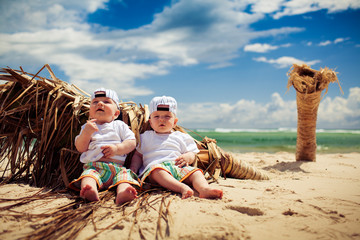 identical twin boys relaxing on a beach