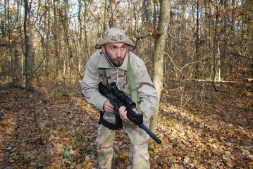 Fototapeta premium Us Marine in a forest with his rifle sniper