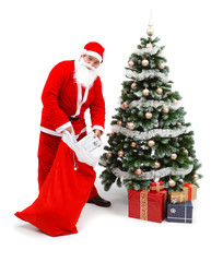 Santa Claus putting gifts under christmas tree