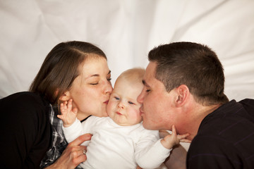 glückliche Eltern küssen ihre Tochter