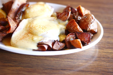 Eggs benedict, bacon, and potatoes