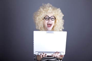Portrait of funny girl in blonde wig with laptop.