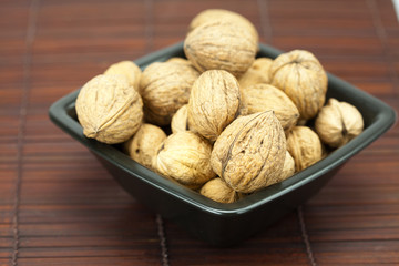 walnuts in a bowl on a bamboo mat