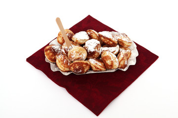 Poffertjes in einer Pappschale auf einer Serviete isoliert