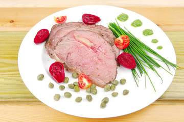 roasted meat served on white dish over wood