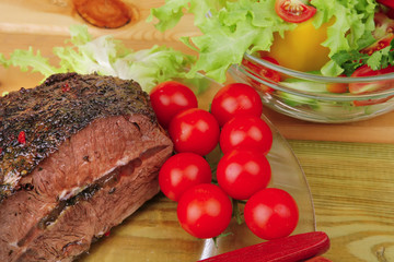 beef on transparent plate with salad bowl