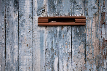 very old postbox in wheathered wooden fence