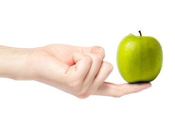 Female hand balancing a fresh wet green apple on finger,
