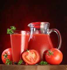 Jug and glass full of tomato juice.