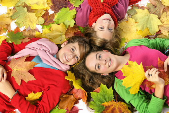 Trois jeunes filles sous les feuilles d'automne