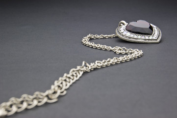 Silver necklace with heart-shaped pendant on a black background
