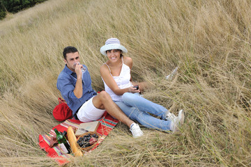 happy couple enjoying countryside picnic in long grass