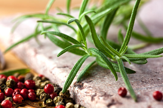Rosemary and peppercorns on a stone background