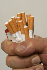 Mann zerdrückt eine Packung Zigaretten