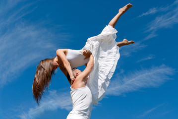 Fototapeta premium young couple dancing on sky background, freedom and relax symbol