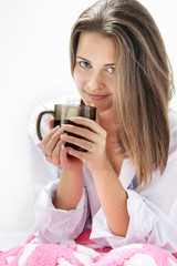 young attractive girl with cup of tea in bed