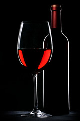 Red wine bottle and glass silhouette over black background
