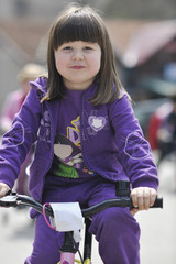 Fototapeta na wymiar cute little girl driving bicyle at sunny day