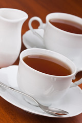 Black tea in mugs with saucers