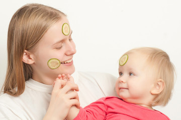 young adorable mother with daughter play with sliced cucumbers o
