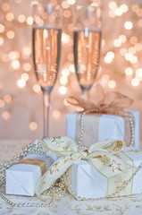 Fototapeta na wymiar Glasses of champagne with gold ribbon gifts