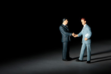 Miniature figurines of handshaking businessmen