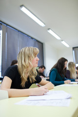 young pretty female college student sitting in a classroom full