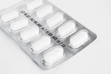 pack of white medicine pills on white background
