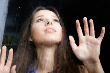 young girl behind wet window