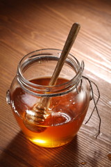 Pot of honey and wooden stick in it.