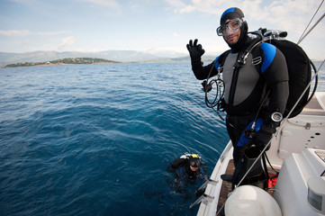 scuba diver standing on the yacht and ready to dive