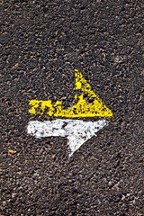 arrow in yellow and white on a paveway for orientation