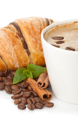 Cup of coffee with coffee beans, cinnamon sticks and chocolate c