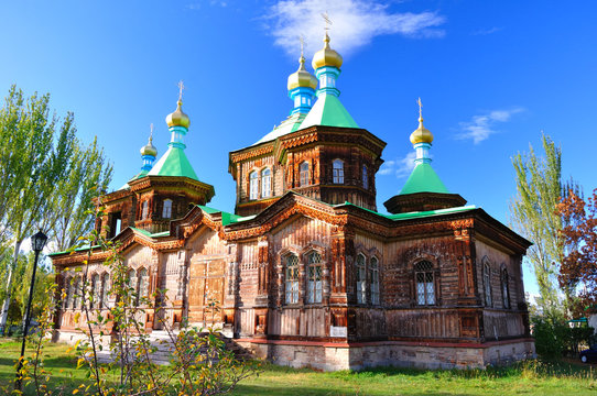 The Russian Orthodox Holy Trinity Cathedral in Karakol, Church,  stands adorned with golden domes and crosses, its wooden frame contrasted the clear blue winter sky