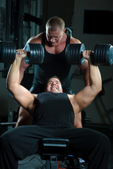 Two bodybuilders training in gym