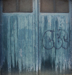 blue grungy wood and metal garage door with graffiti