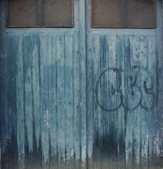 blue grungy wood and metal garage door with graffiti