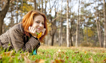 Portrait of red-haired girl in the autumn park.