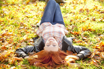 Happy red-haired girl at the park in autumn.