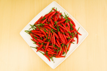 Hot peppers in the plate on wooden table