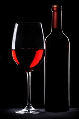Red wine bottle and glass silhouette over black background