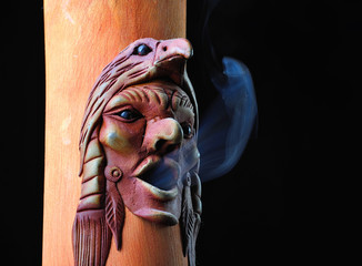 Bamboo incense holder with smoke on a black background.
