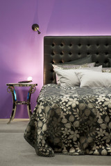 Bett vor einer lilafarbenen Wand