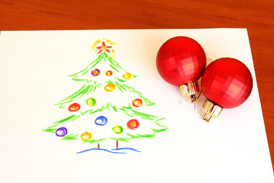 Child's drawing and christmas balls on the table