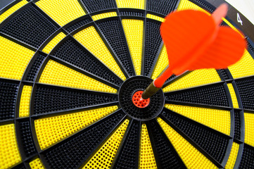 Red dart arrow in bulls eye in dart game board