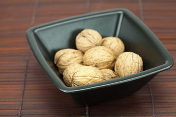 walnuts in a bowl on a bamboo mat